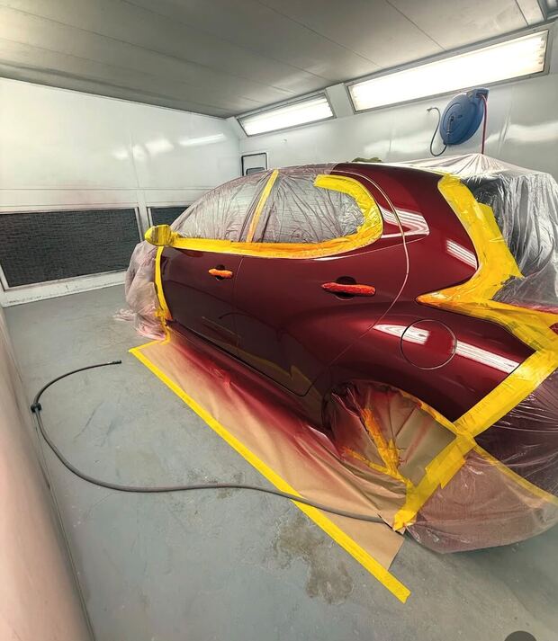 The same Toyota Yaris masked up in the booth, painted back to deep red