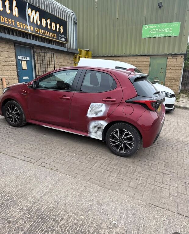 Dark red Toyota Yaris outside the workshop with the rear door and quarter filled and primed