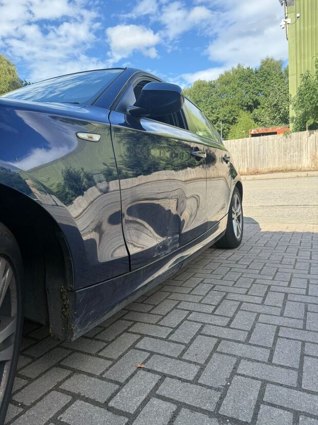 Dark blue BMW outside the workshop with the driver's door and sill damaged