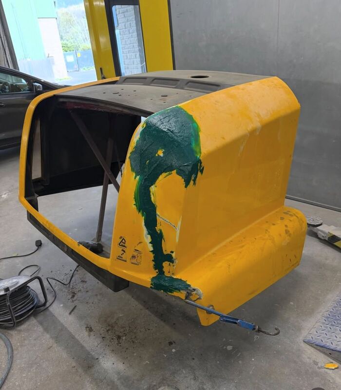 The same JCB panel with green fibreglass laid over the crack and the broken edge