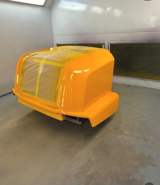 The same JCB engine cover finished in gloss yellow in the spray booth