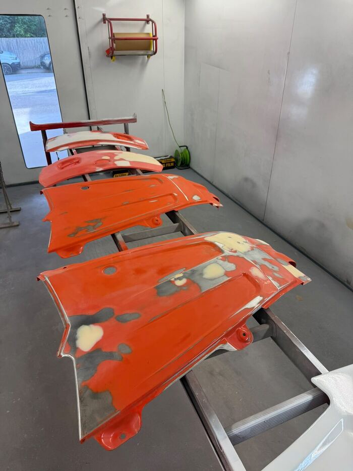 Orange Kubota panels on stands with filler and primer patches showing