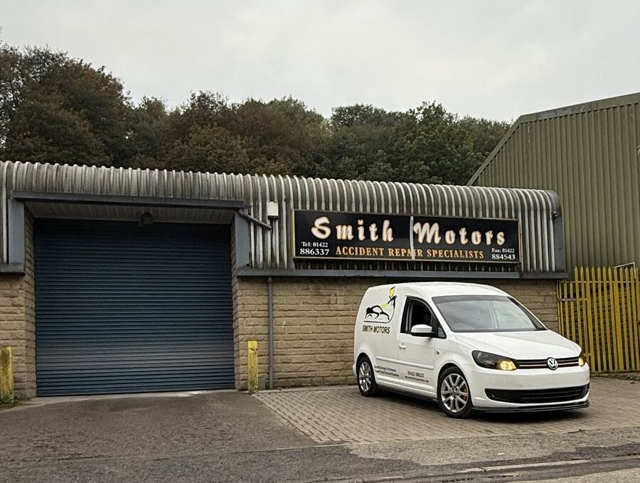 The Smith Motors unit — a roller shutter under a black and gold sign reading Smith Motors, Accident Repair Specialists, with the white Smith Motors van parked outside